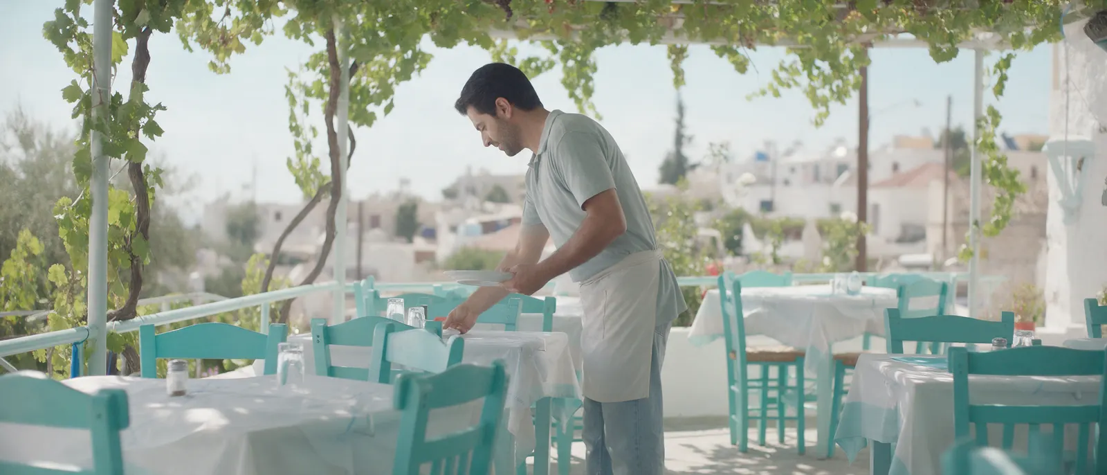 A restaurant owner sets the terrace tables at opening time.